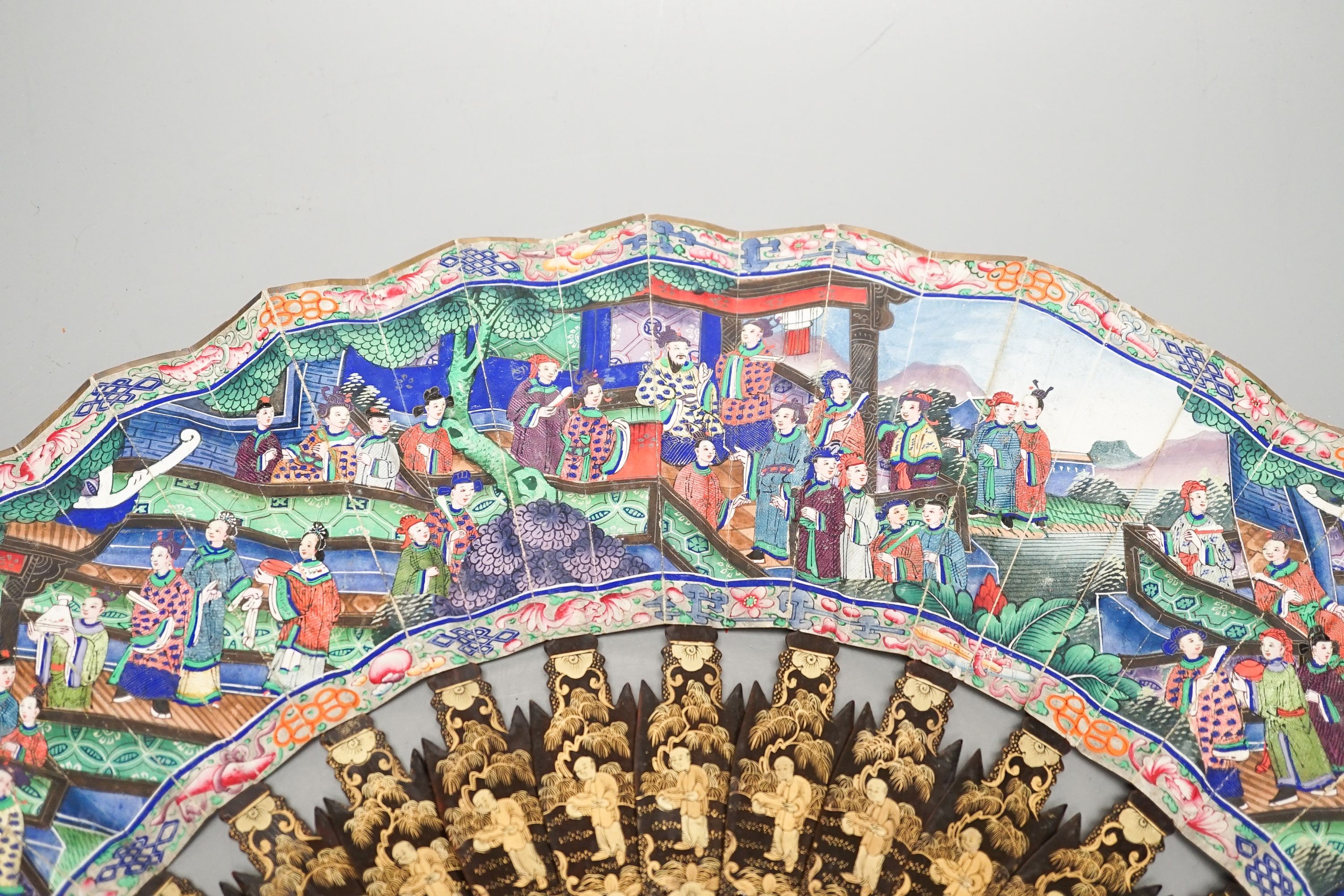 A Chinese export gilt decorated lacquer fan and box, mid 19th century, the appliqué work paper fan leaf decorated with figures amid pavilions and trees, box 32cm